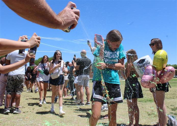 A parent uses silly string on a student to celebrate the last day of school