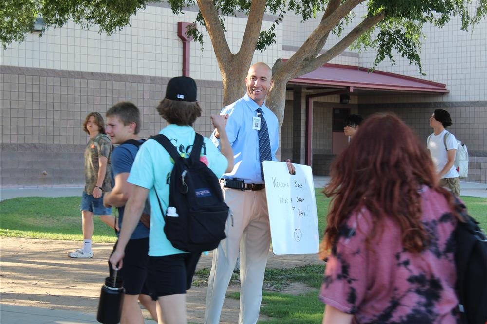 Principal Marques Reischl fist bumps a student as he walks onto campus