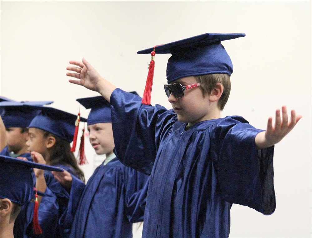 Student wears a cap and gown with red, white, and blue American flag sunglasses