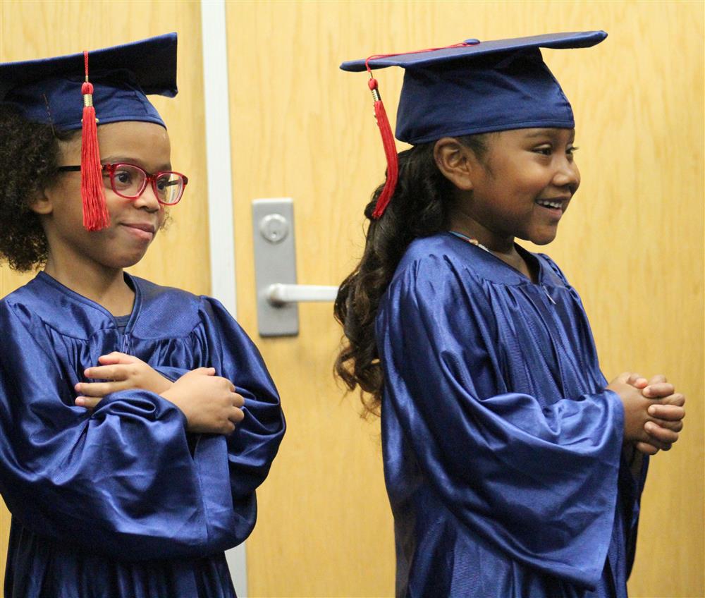 Two kindergarten student wearing a cap and gown