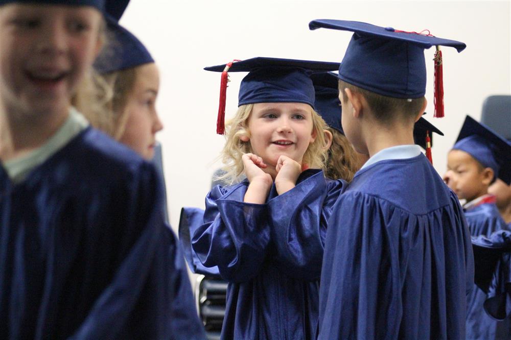 Two kindergarten students wearing caps and gowns