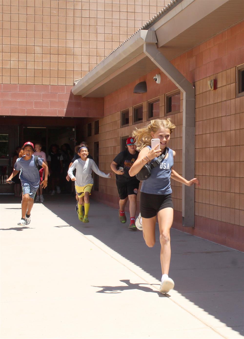 Students run out of the school and into the sunlight